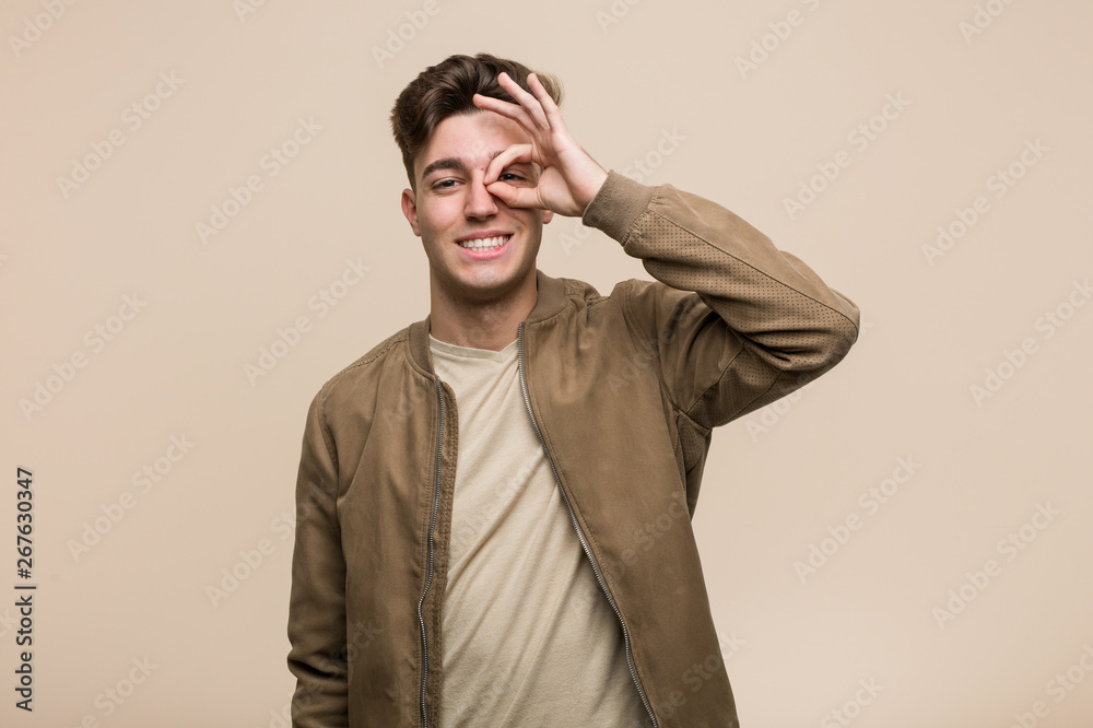 Obraz premium Young caucasian man wearing a brown jacket excited keeping ok gesture on eye.