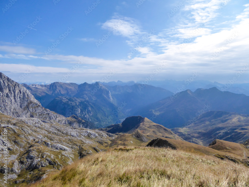 A hiking trail in the high mountain peaks. Lush green grass covers the slopes. Some crocuses are blossoming. Spring in the mountains. Nature wakes up after the hibernation period. Beautiful day.