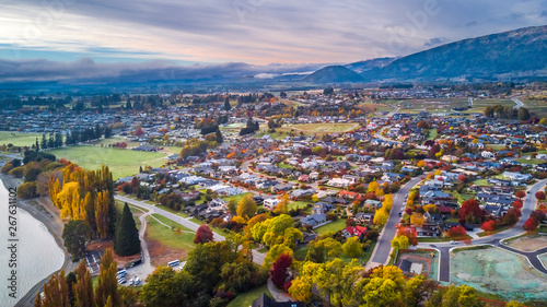 Small town surrounded by yellow autumn trees at the foot of mountain ridge. Wanaka, Otago, South Island, New Zealand photo