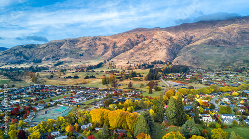 Small town surrounded by yellow autumn trees at the foot of mountain ridge. Wanaka, Otago, South Island, New Zealand