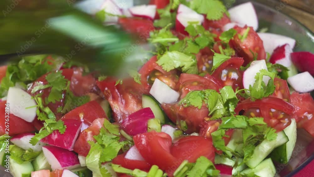 Close-up, the process of dressing a salad of fresh colorful vegetables tomatoes cucumbers radishes with cheese and herbs olive oil, healthy food, vegetarian cuisine Close-up, the process of dressing a salad of fresh colorful vegetables tomatoes cucumbers radishes with cheese and herbs olive oil, healthy food, vegetarian cuisine