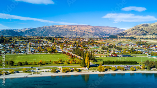 Small town surrounded by yellow autumn trees at the foot of mountain ridge. Wanaka, Otago, South Island, New Zealand