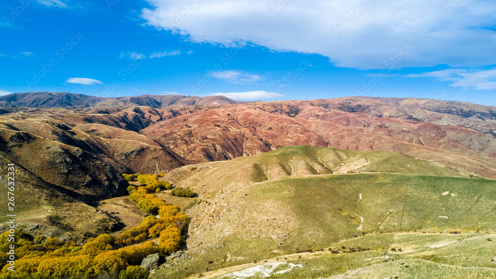 Obraz premium Hill terrain with small rivers and valleys on a sunny day. Otago, South Island, New Zealand