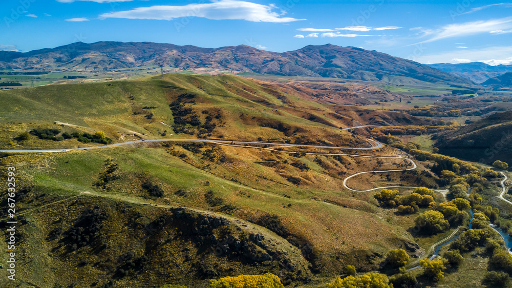 Naklejka premium Road running through hills and farmland. Otago, South Island, New Zealand