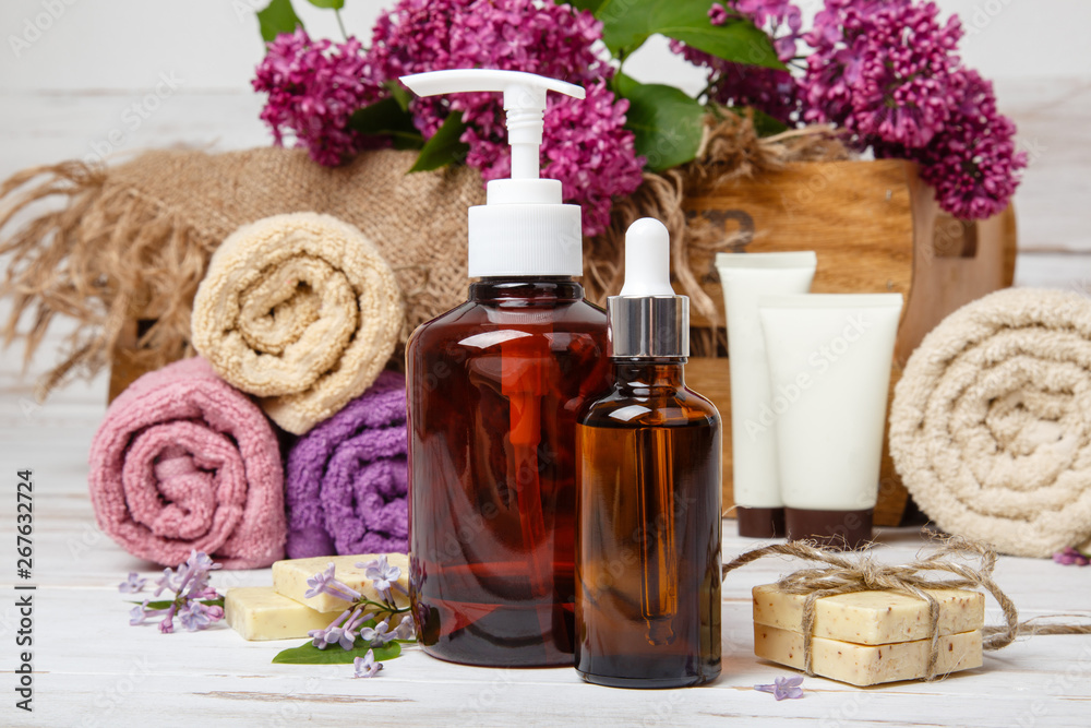 Natural cosmetics with lilac flowers. Serum, soap and cream with towel rolls. Natural cosmetics with lilac flowers. Serum, soap and cream with towel rolls.