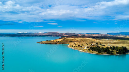 Hills on a shore of a beautiful lake with mountain range on the background. Otago  South Island  New Zealand