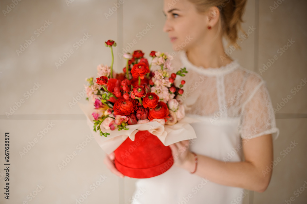 Young girl holds red hat box with flower bouquet Young girl holds red hat box with flower bouquet