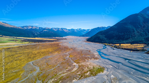 River running across alpine valley surrounded by rocky mountains. West Coast, South Island, New Zealand