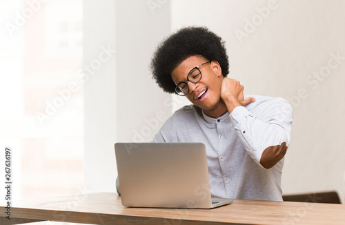 Young black man using his laptop suffering neck pain