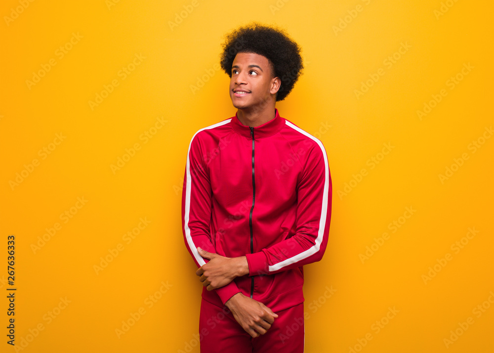 Young sport black man over an orange wall dreaming of achieving goals and purposes