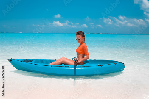 Sexy brunette paddling a kayak. Woman exploring calm tropical bay. Maldives. Sport, recreation. Summer water sport, adventure outdoors. © Victoria Andreas