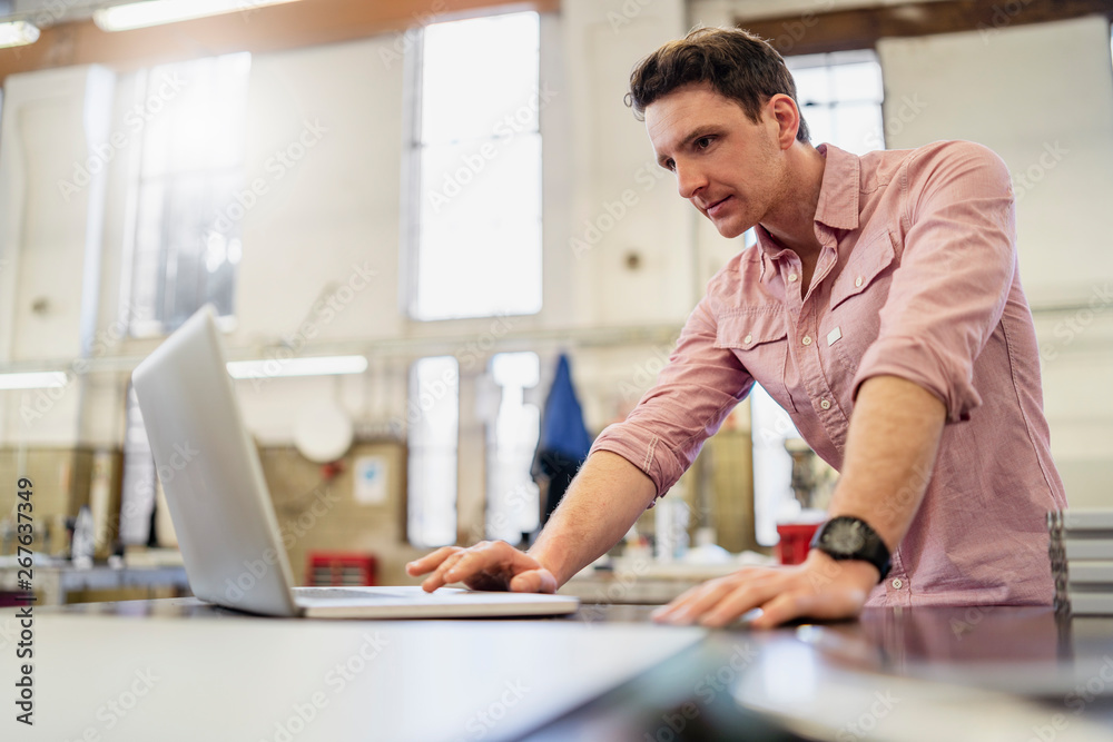 Man using laptop in factory Man using laptop in factory
