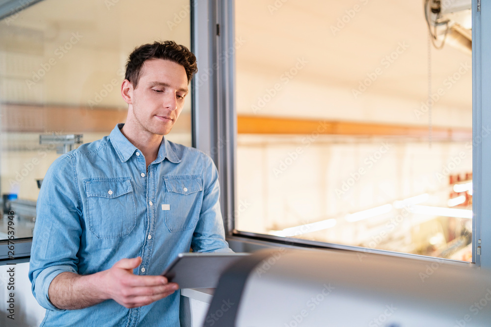 Businessman using tablet at the window with factory background