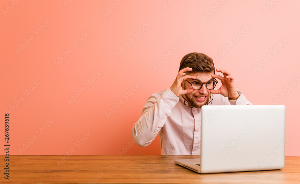 Young man working in a call center keeping eyes opened to find a success opportunity.