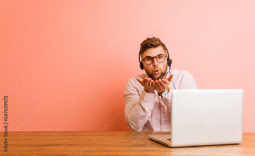 Young man working in a call center folding lips and holding palms to send air kiss.