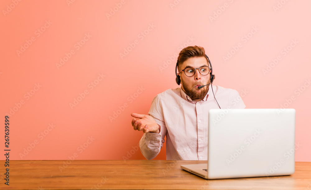 Young man working in a call center shrugs shoulders and open eyes confused.