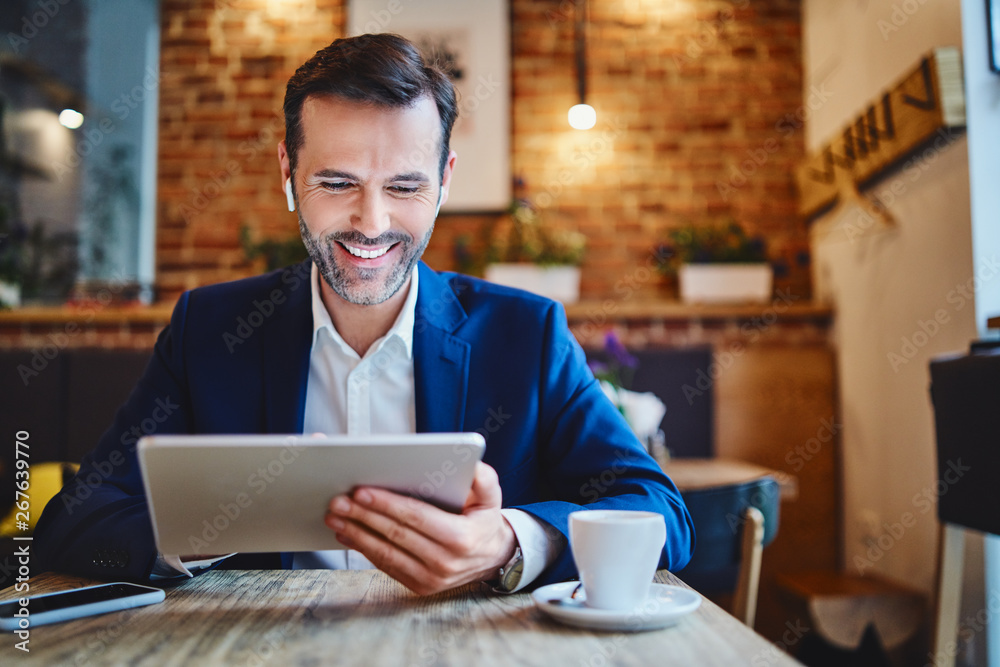 Portrait of businessman with wireless headphones using tablet in cafe Portrait of businessman with wireless headphones using tablet in cafe
