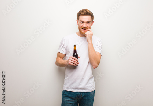 Young redhead man. Holding a beer.