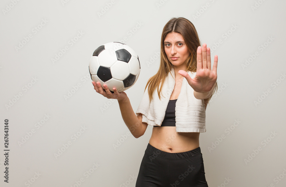 Young fitness russian woman putting hand in front. Holding a soccer ball.