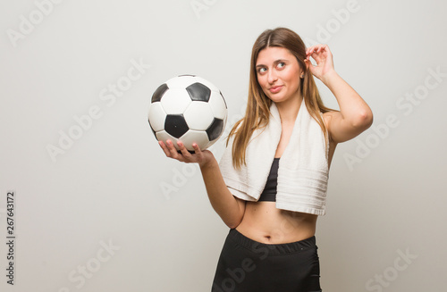Young fitness russian woman dreaming of achieving goals and purposes. Holding a soccer ball. © Asier