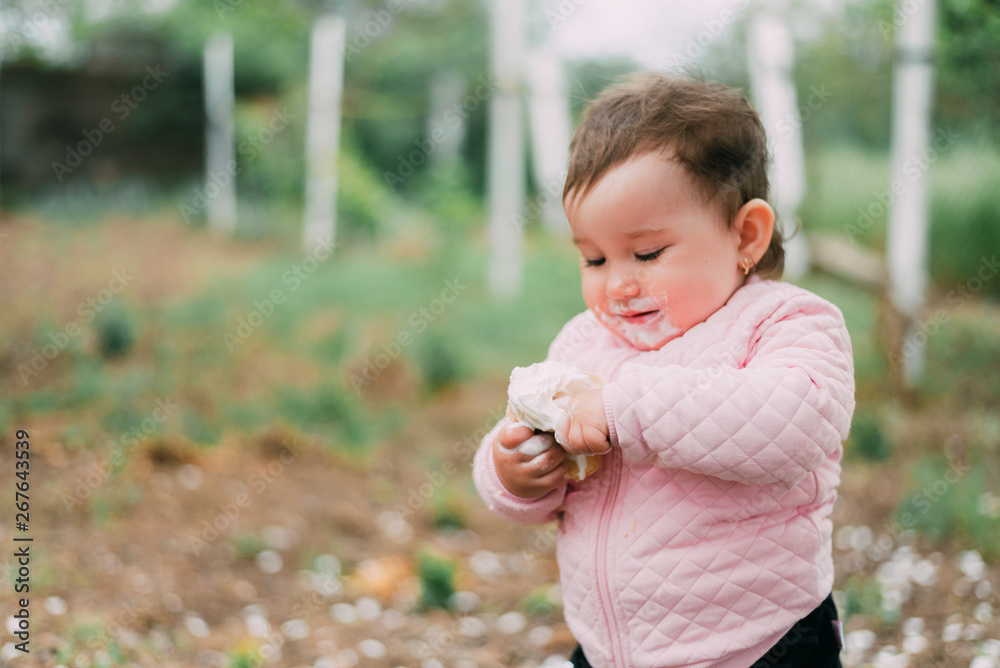 little girl in the garden on the background of greenery and trees very cute eating ice cream finger in a waffle Cup little girl in the garden on the background of greenery and trees very cute eating ice cream finger in a waffle Cup