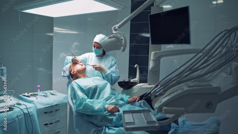 Dentist with young assistant treating the clients' teeth on the