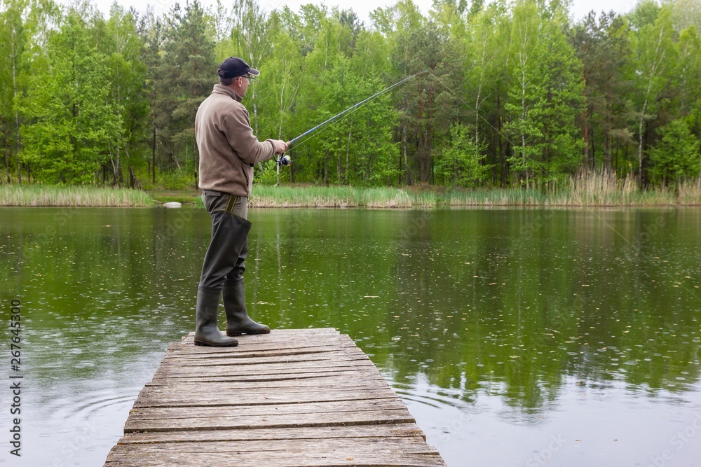 Angler catching the fish from wooden pier during rain