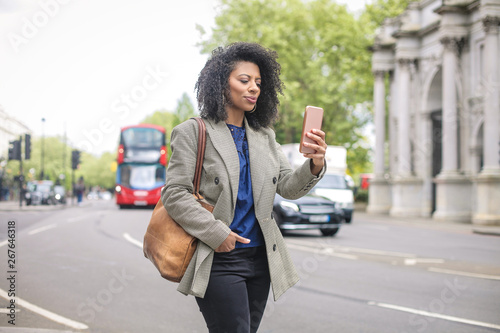 Photography Business woman walking in the street, checking her smart phone