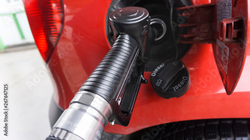 A red car is at a gas station and is fueled with diesel. Closeup of the tap and the tank. photo