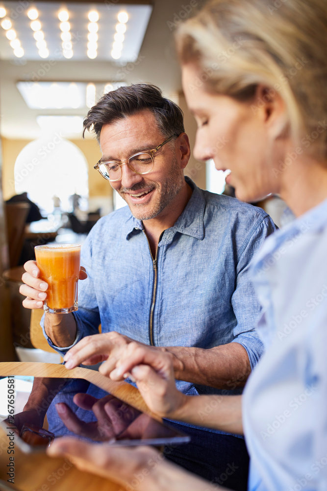 Smiling woman and man using tablet in a cafe Smiling woman and man using tablet in a cafe
