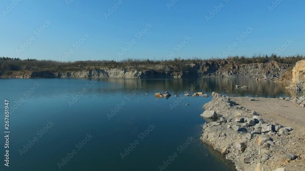 Picturesque landscape the azure lake in a flooded granite quarry. Rocky granite stone shores. Turquoise water and blue sky. Drone aerial survey view Picturesque landscape the azure lake in a flooded granite quarry. Rocky granite stone shores. Turquoise water and blue sky. Drone aerial survey view