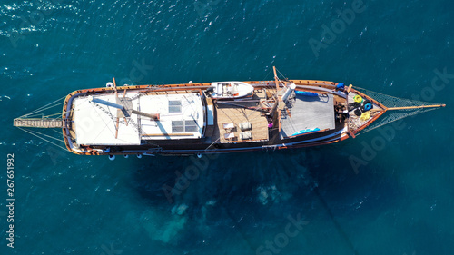 Aerial birds eye drone view of beautiful wooden sailboat in deep blue sea of island of Mykonos, Cyclades, Greece © aerial-drone