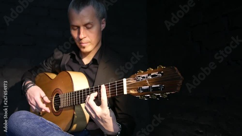 guitarist plays flamenco on an acoustic guitar against a black brick wall,isolated
