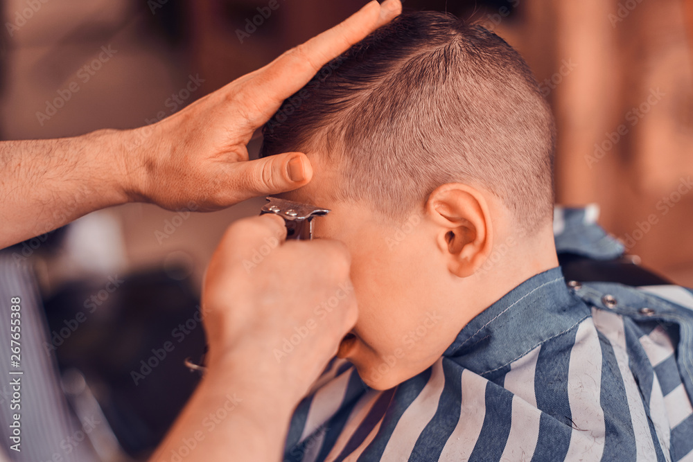Little pretty school boy had his first trendy haircut at modern barbershop. Little pretty school boy had his first trendy haircut at modern barbershop.