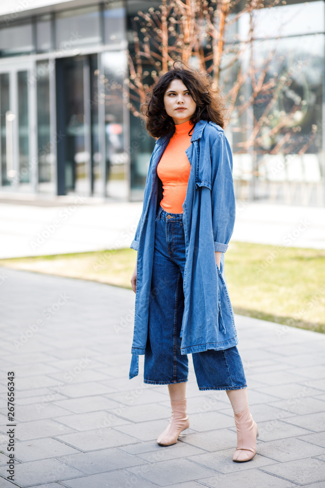 Young pretty girl walking on the street, dressed in jeans and denim shirt. Student weekdays