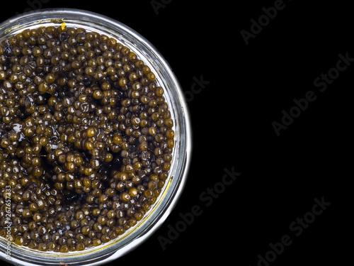 Black caviar in a little bowl on a black background, top view