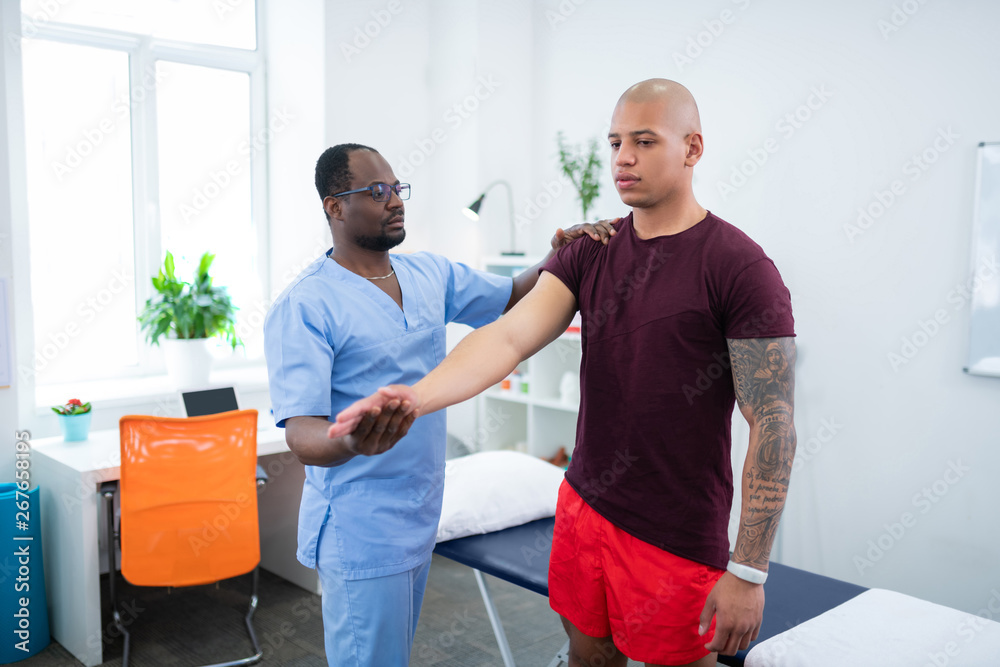 Obraz premium Young bodybuilder wearing smart watch visiting physical therapist