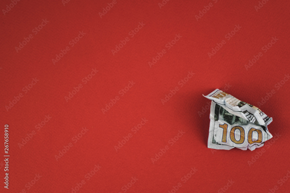 crumpled hundred dollar bill lying on a red background crumpled hundred dollar bill lying on a red background