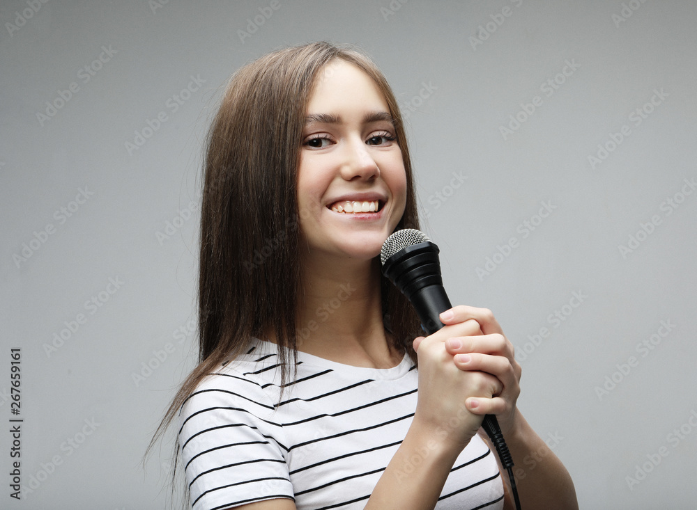 Beauty model girl singer with a microphone over light grey background Beauty model girl singer with a microphone over light grey background