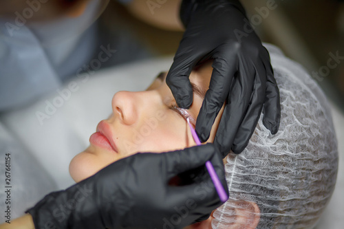 Permanent make up eyeliner procedure  applying on young girl. Close-up. Young beautiful woman making permanent makeup in cosmetology salon. Young girl applying permanent eyeliner in beauty studio