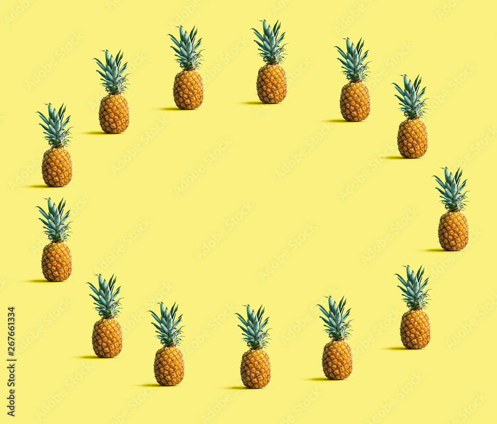 Fototapeta premium Round frame of pineapples on a solid color background