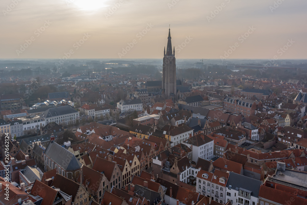 Fantastic Bruges city skyline with red tiled roofs and Church of Our Lady tower in winter day. View to Bruges medieval cityscape from the top of the Belfry Tower.