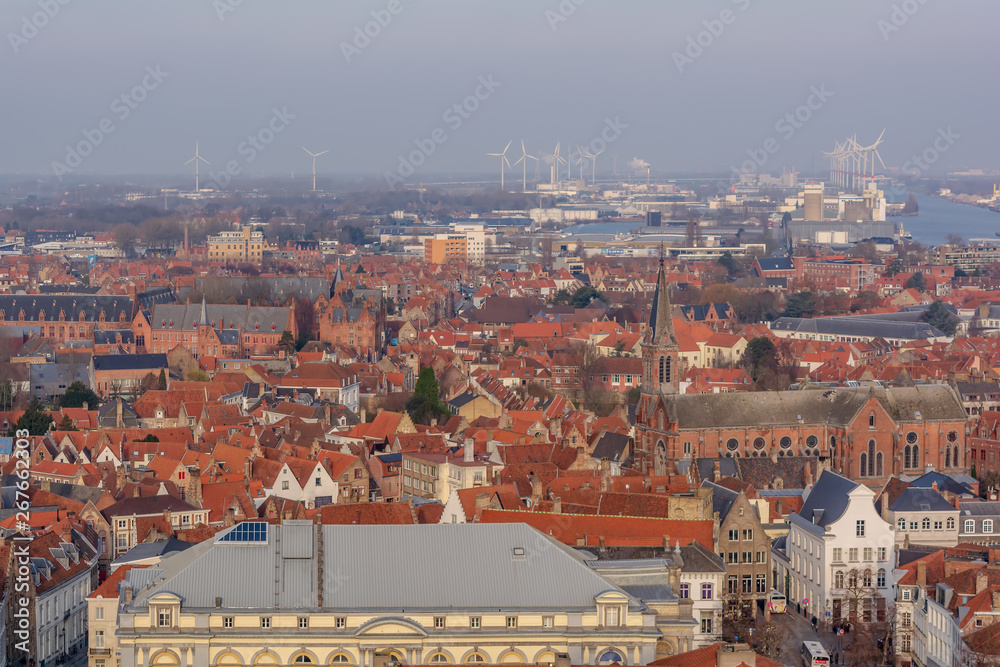 Fantastic Bruges city skyline with red tiled roofs, Heilig Hartkerk (church of the Holy Heart) and windmills in the background. View to Bruges medieval cityscape from the top of the Belfry Tower.