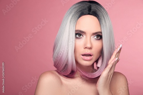 Ombre bob short hairstyle. Beautiful hair coloring woman with wow face holding hand near her cheek isolated on pink studio background.