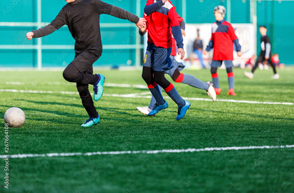 Boys at black red sportswear run, dribble, attack on football field. Young soccer players with ball on green grass. Training, football, active lifestyle for kids Boys at black red sportswear run, dribble, attack on football field. Young soccer players with ball on green grass. Training, football, active lifestyle for kids