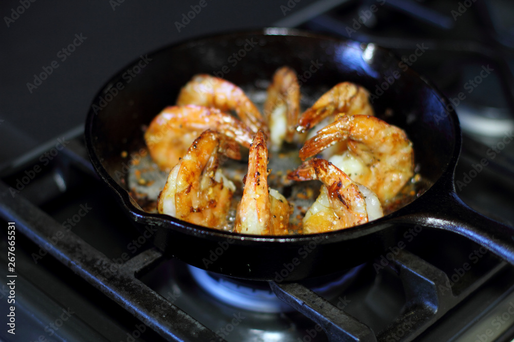 Shrimp Scampi cooking in a cast iron pan on the stove.