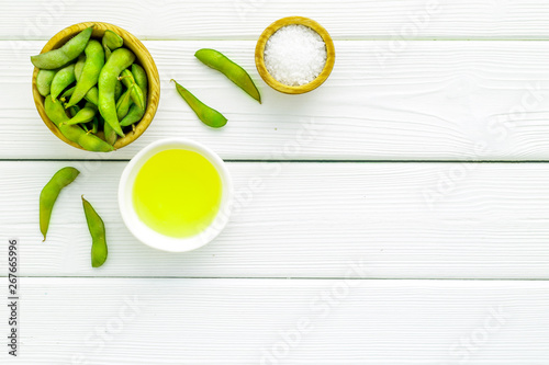 Fresh edamame and oil on white wooden background top view mock up