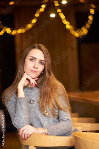 Portrait of young attractive smiling woman with long hair wearing grey sweater. © Kiryl Lis