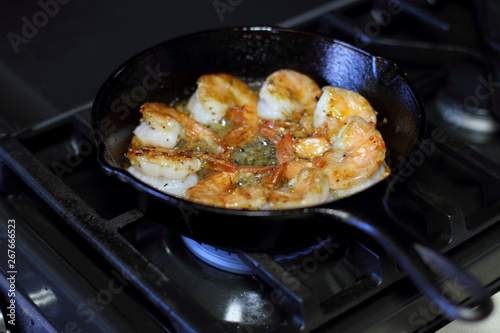Shrimp Scampi cooking in a cast iron pan on the stove.