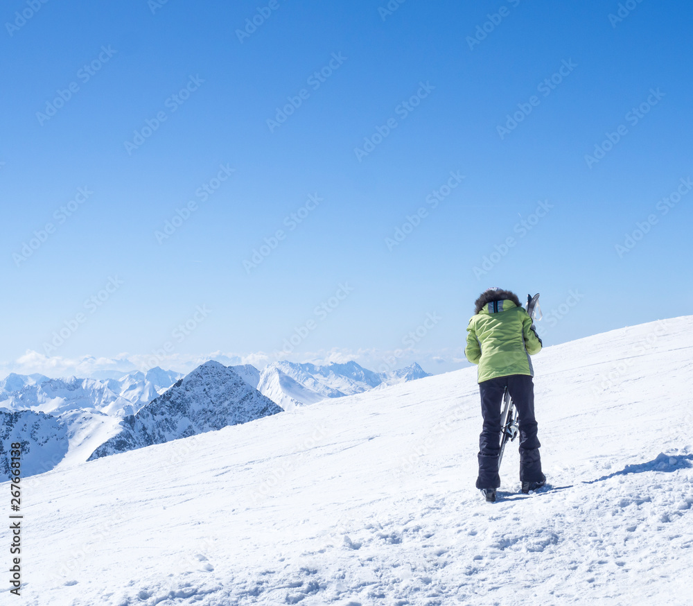 Skier at the top of Schaufelspitze mountain at Stubai Gletscher ski resort preparing to go down into the valley. Snow covered peaks. South Tyrol, Austrian Alps. Nature and sport background, blue sky